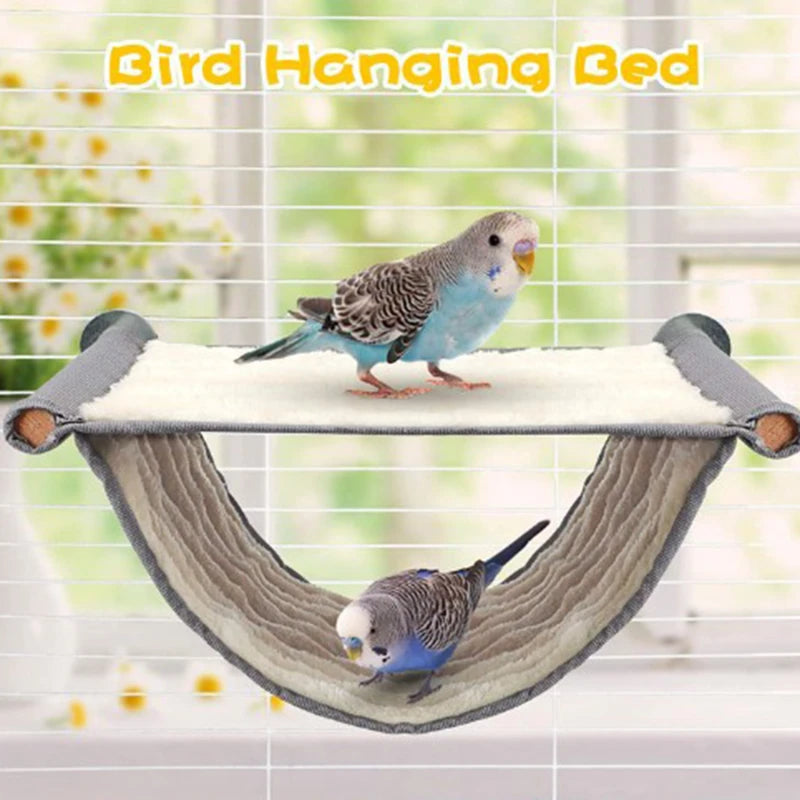 A small blue and gray parrot is perched on a cozy fleece bird hammock designed for hanging.