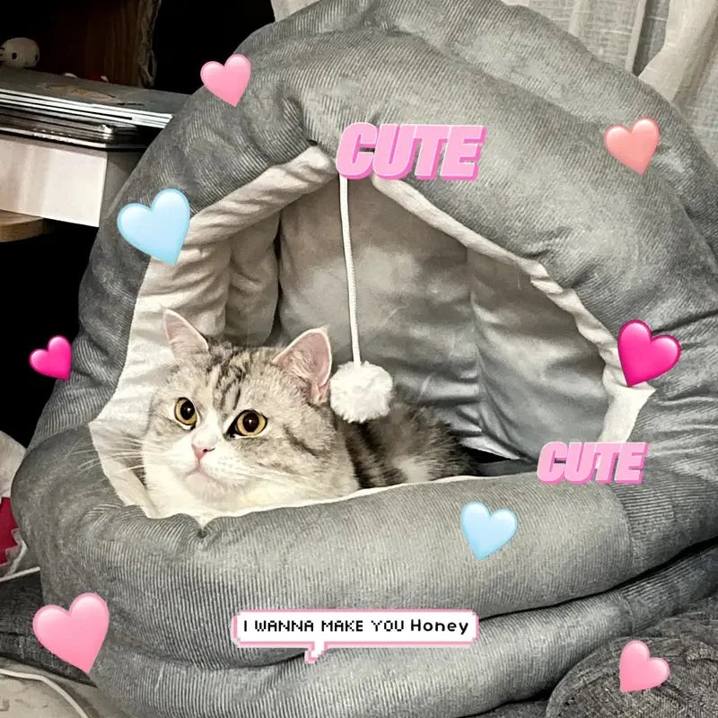 A fluffy gray and white cat is relaxing inside a cozy plush nest bed with a hood.