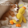 A fluffy dog is resting next to a yellow plush duck toy on a white bed.