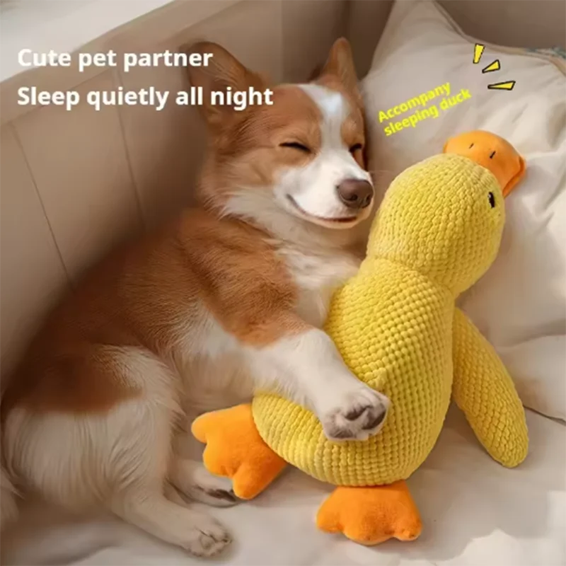 A fluffy dog is resting next to a yellow plush duck toy on a white bed.