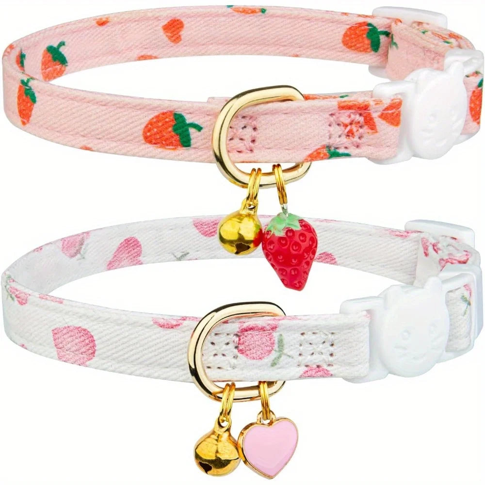 A pink and white cotton breakaway cat collar with strawberry and heart designs, featuring a safety buckle and bell.