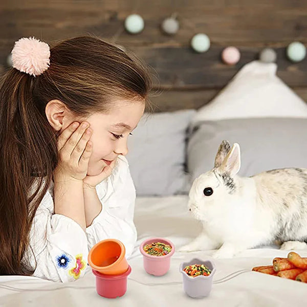 A young girl is interacting with rabbit stacking puzzle cups and food items on a white surface.