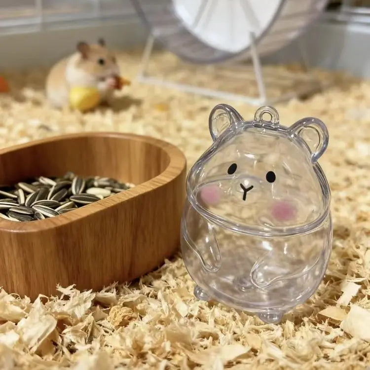 A clear glass figurine shaped like a cute bear is placed on wood shavings next to a wooden bowl.