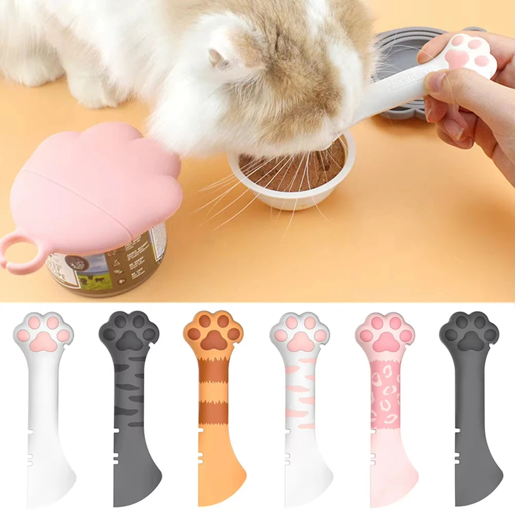 A hand is using a pink silicone cat paw opener and food scoop with a lid to access food from a container.
