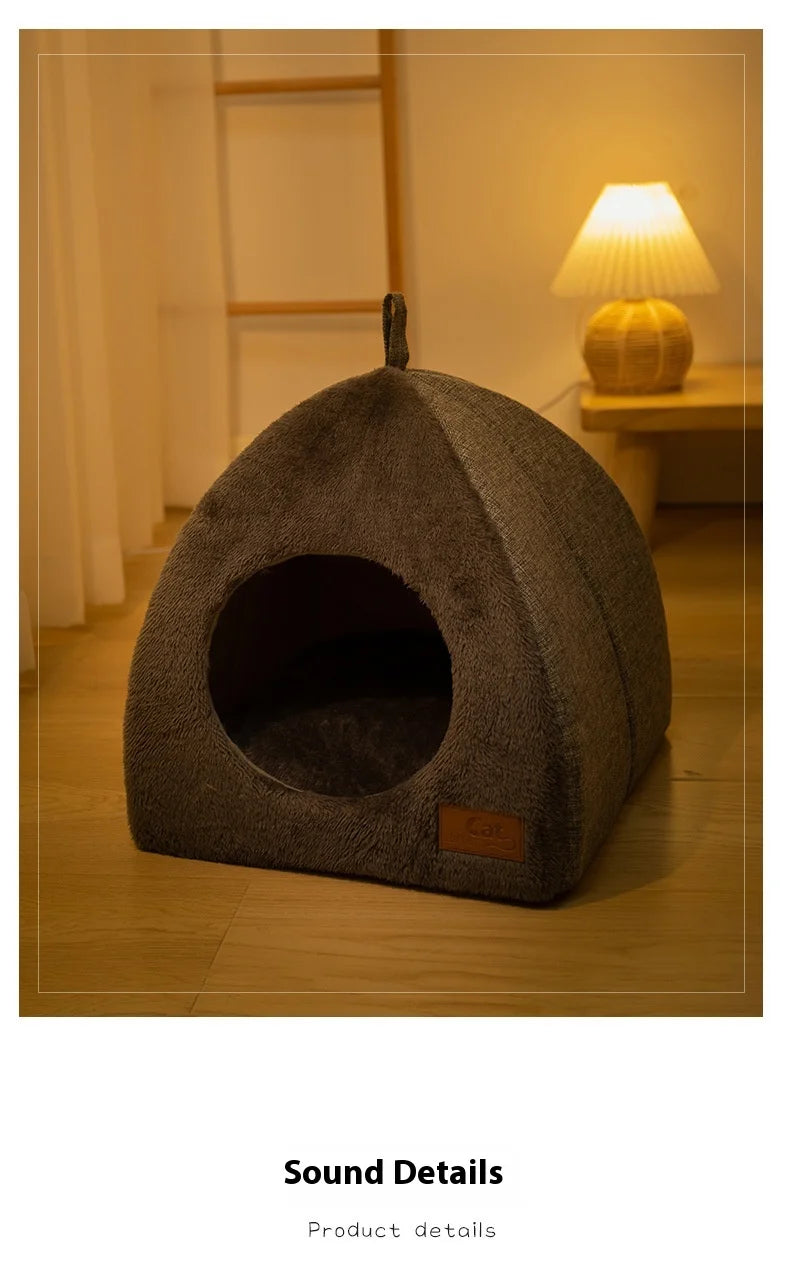 Un lit nid pour chat rond et gris en velours posé sur un plancher en bois à côté d'une lampe.