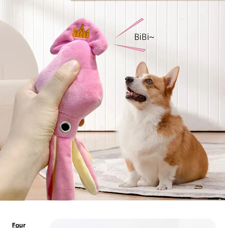 A hand holds a pink squeaky octopus dog toy with a cotton rope tail next to an orange and white dog.