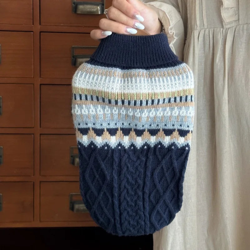 A close-up of a navy blue knit sweater with beige and gray stripes being held by a person.