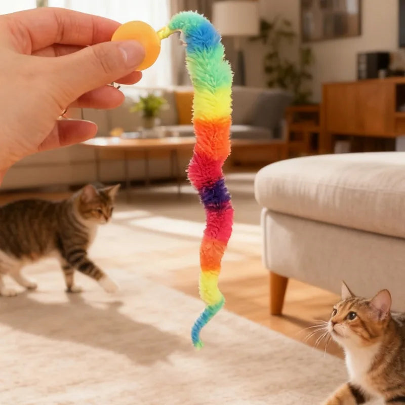 A hand holds a colorful, fuzzy caterpillar toy with bright stripes, near a domestic cat.