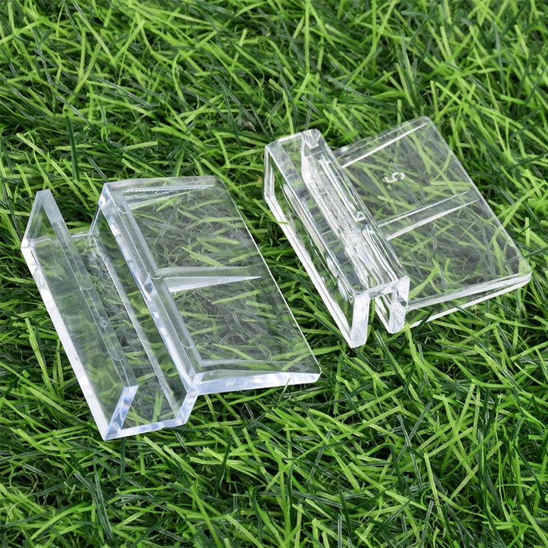 Klare Acrylglas-Deckelclips liegen auf grünem Gras