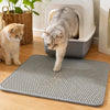 A gray cat walks on a gray double-layer litter mat indoors.