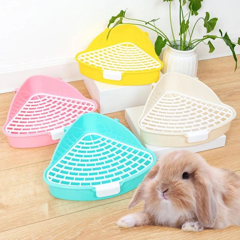 A collection of colorful plastic litter boxes in pink, yellow, and teal, with a fluffy rabbit resting nearby.