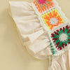 A close-up of a cream-colored toddler romper featuring colorful floral embroidery on the shoulder and sleeve.