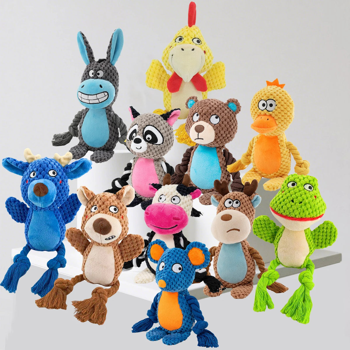 A collection of colorful plush animal toys including a blue dog, yellow bird, brown bear, and green frog.