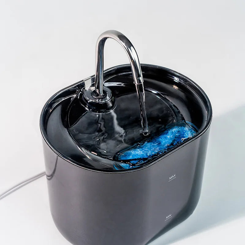 A black cat water fountain with a stainless steel faucet pouring water into the bowl.