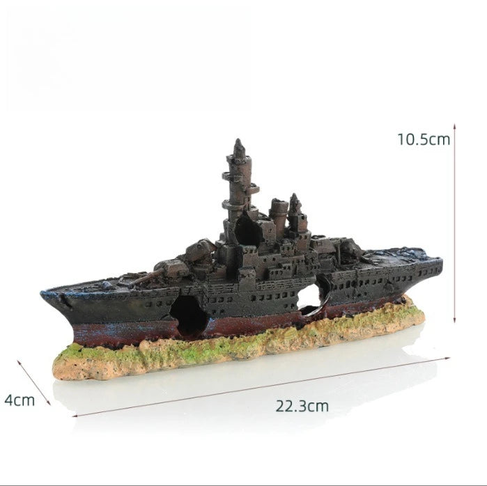 A miniature model of a sunken ship with a cave hideout, painted dark colors and featuring rough terrain.
