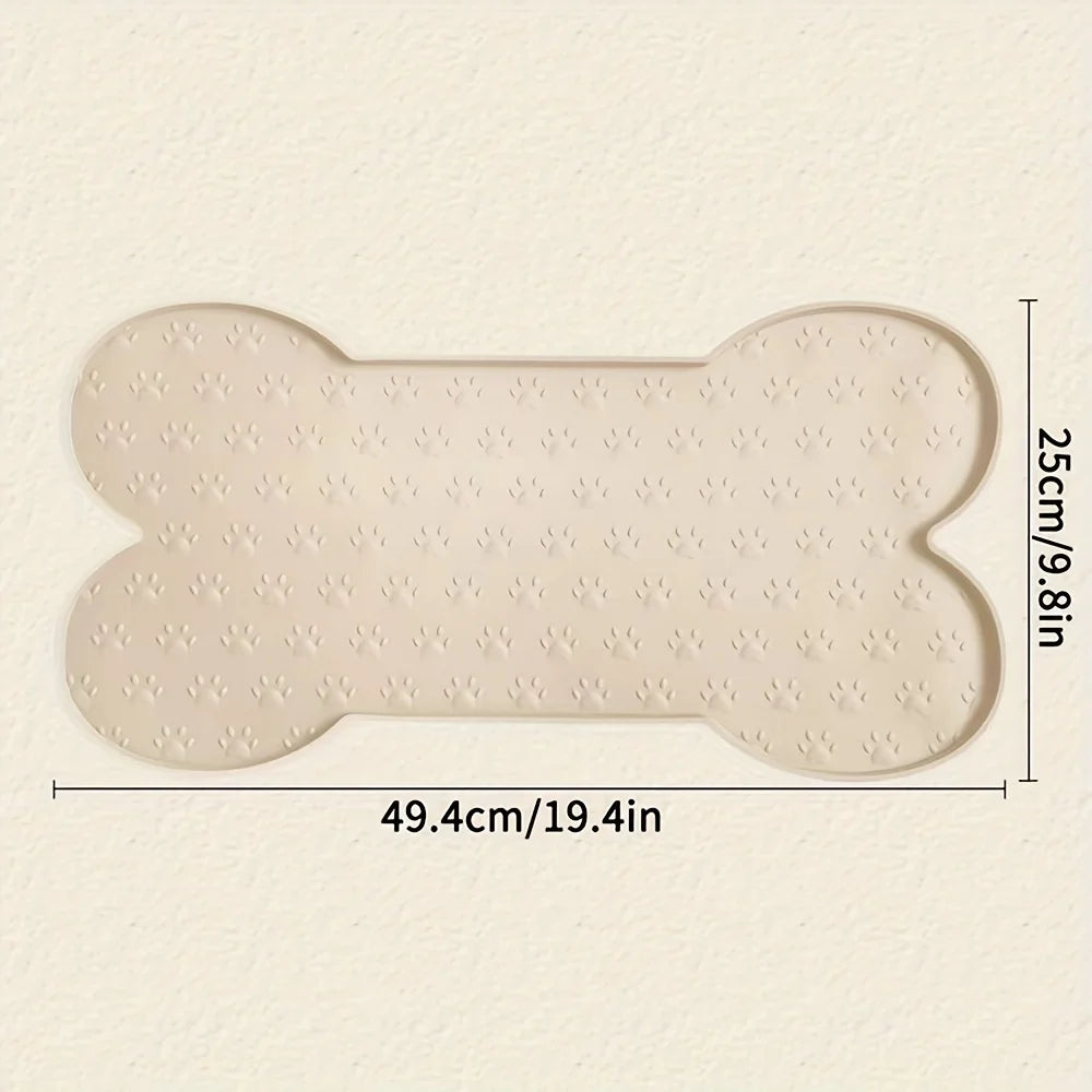 A beige non-slip silicone dog feeding mat shaped like a bone with raised edges, measuring 49.4cm by 25cm.
