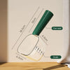 A clear glass measuring scoop with a green handle and scale markings, used for pet food measurement.