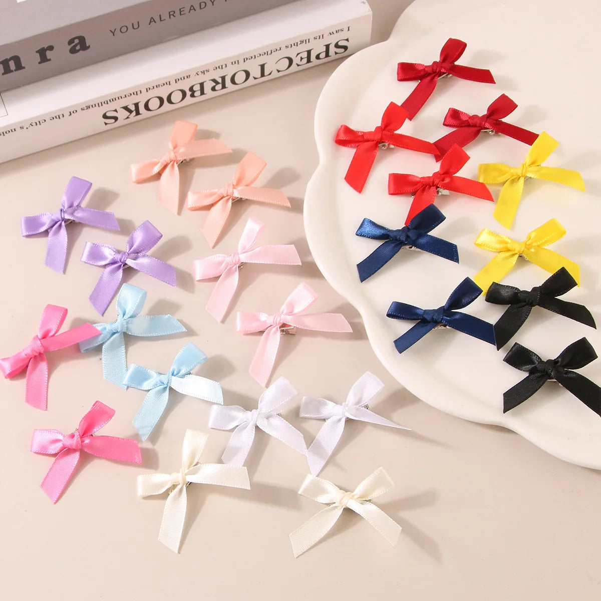 A collection of colorful ribbon bow hair clips in red, pink, yellow, blue, and black arranged on a white plate.
