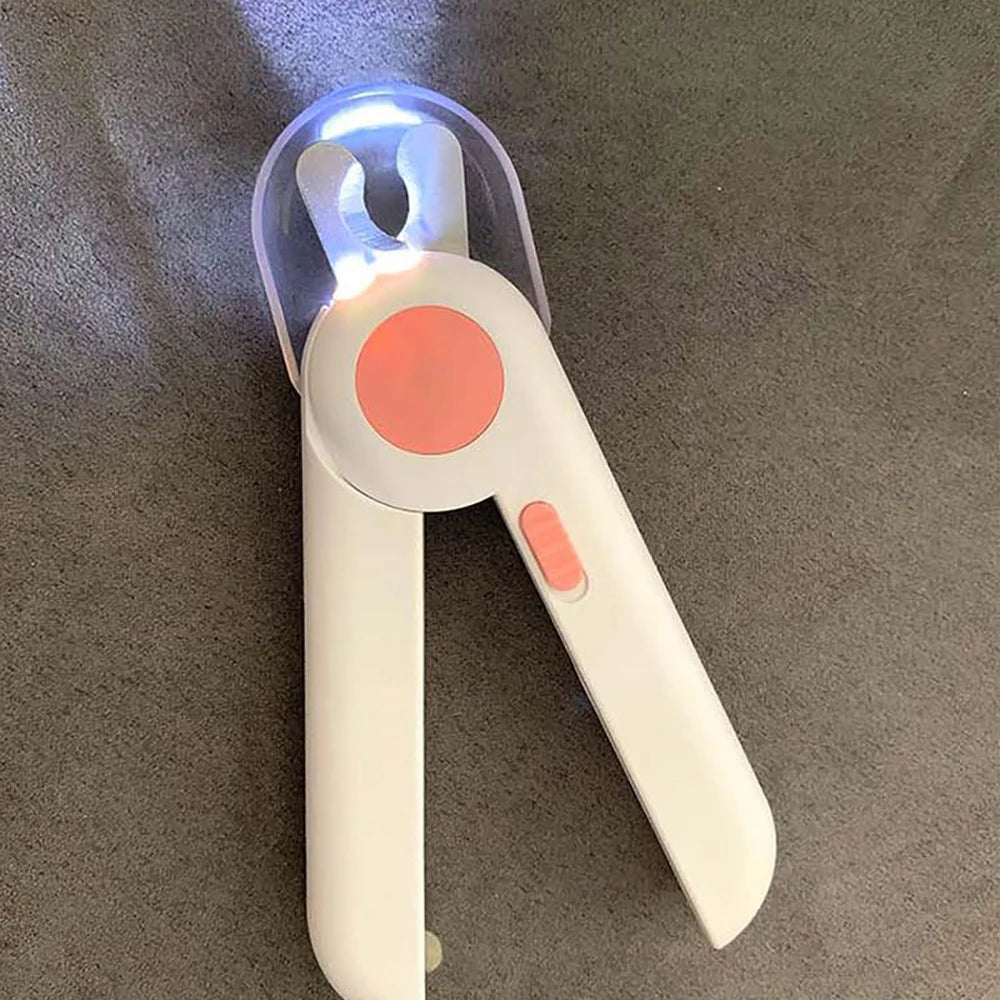 A white LED pet nail clipper tool with a clear light and an orange button, shown against a gray background.