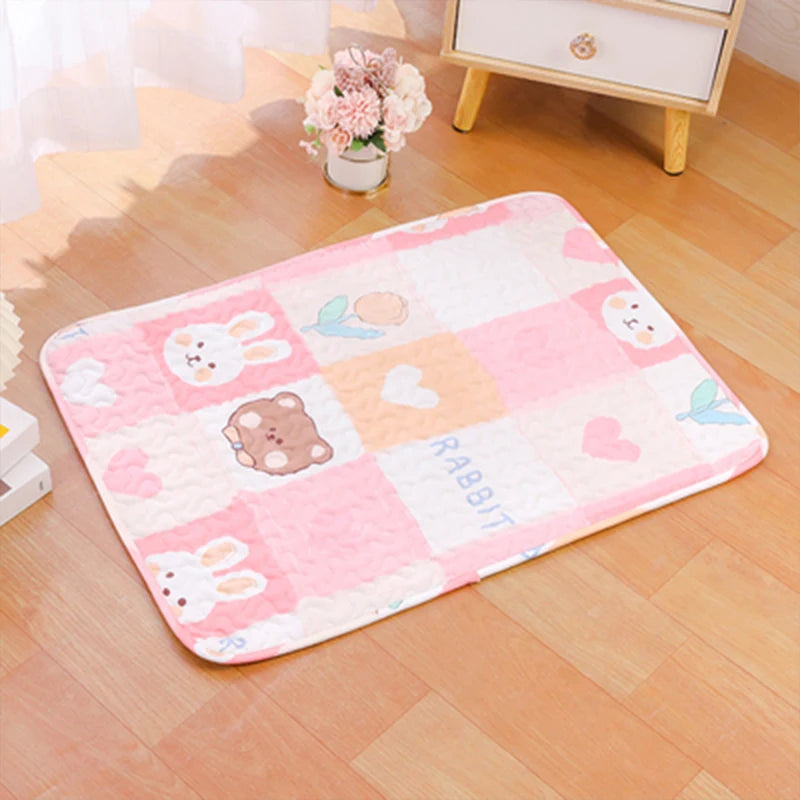 Pink and white checkered pet cage mat featuring rabbit and bear designs on a wooden floor.