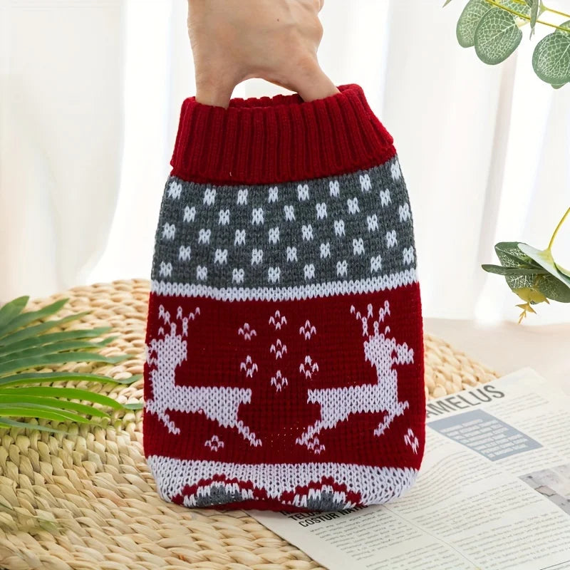 A hand is holding a festive knit pet sweater for dogs and cats featuring a red and gray patterned design.
