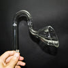 A hand holds a clear borosilicate glass lily pipe, shaped like a curved tube with a flared end.