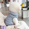 Ein flauschiges weißes Haustierkleid wird von einer Person gehalten und liegt auf einer hellen Oberfläche.