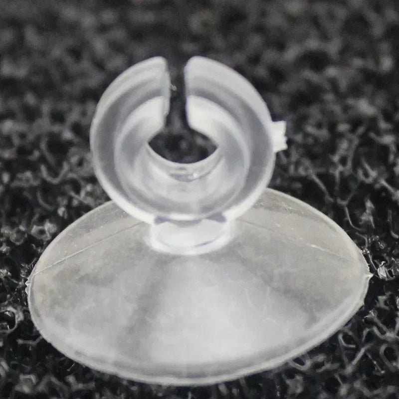 A clear suction cup product with a central opening is shown against a dark, textured background.