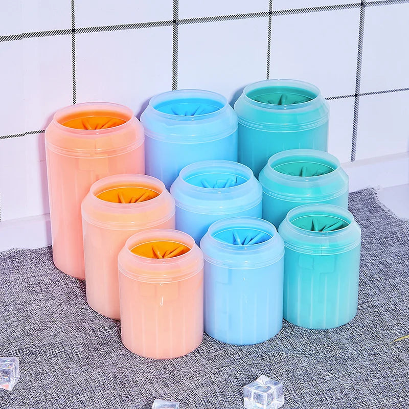 A collection of five portable paw washer cups in various shades of blue and orange silicone with soft bristles.