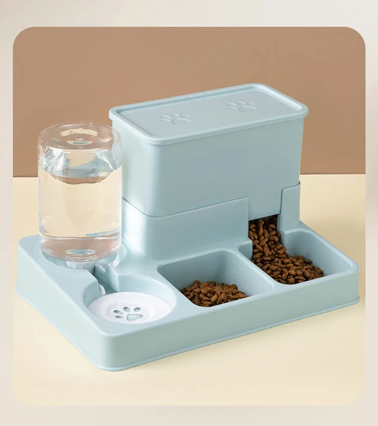 A light blue automatic cat feeder and water fountain device with a glass of water and dry food visible.