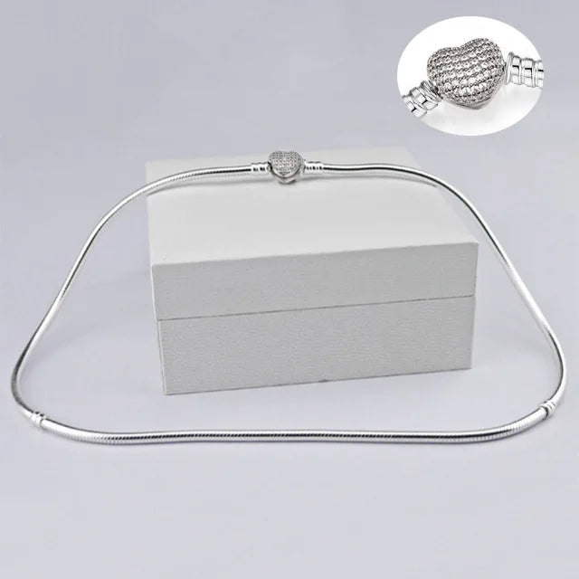 Sterling silver snake chain necklace with a heart charm displayed on a white box.