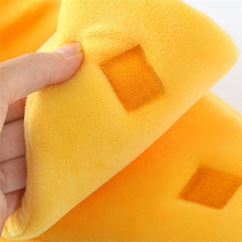 Une main tient un lit pour chat jaune vif en forme de banane avec une tache orange.