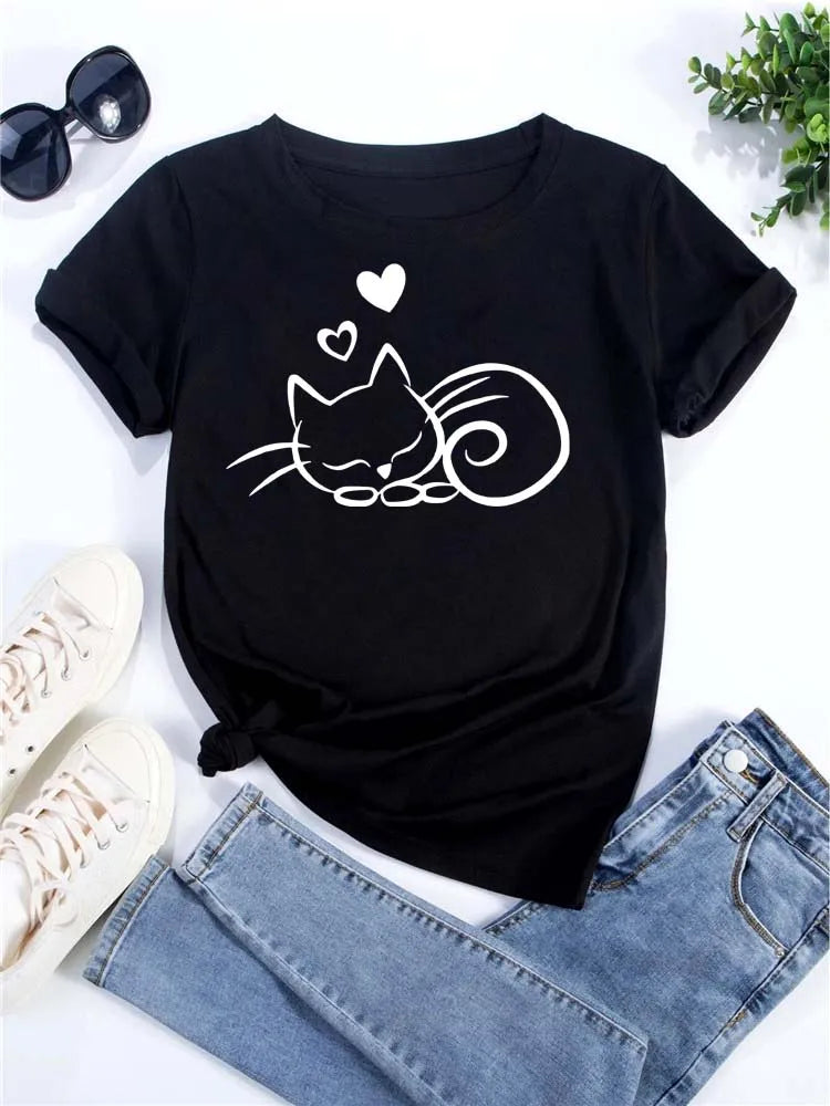 Camiseta negra de manga corta con diseño de gato en blanco, junto a gafas de sol y jeans.