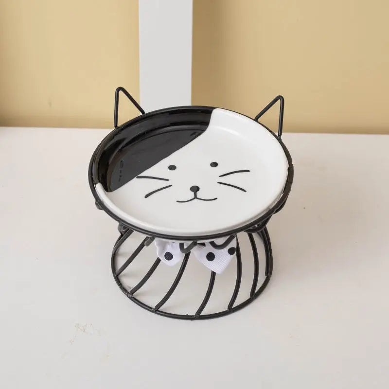 An elevated ceramic cat food dish with a non-slip stand featuring a black and white design.