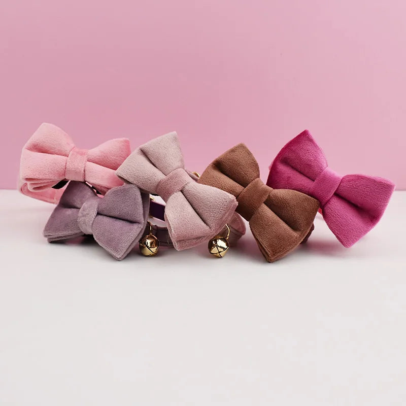 A row of velvet cat collars in various shades of pink and mauve with gold-toned nameplates