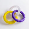 Three colorful TPR pull ring dog chew toys in yellow, purple, and clear with confetti specks.