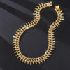 A close-up of a gold spiked Cuban chain bracelet with diamond accents lying on a dark surface.