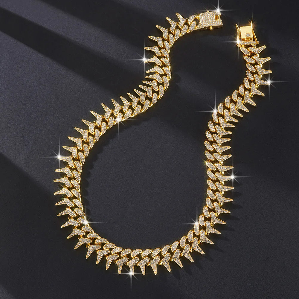 A close-up of a gold spiked Cuban chain bracelet with diamond accents lying on a dark surface.