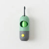A green and gray capsule dog waste bag dispenser with a flashlight top.