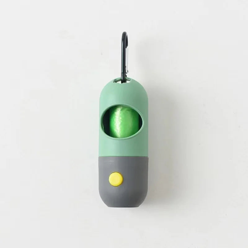 A green and gray capsule dog waste bag dispenser with a flashlight top.