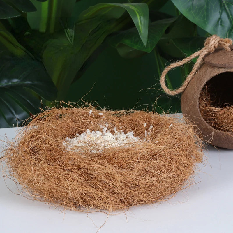 A nest made of natural coconut fiber with white bedding inside, set against a dark green leaf background.