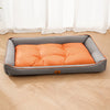 A gray pet sofa bed with an orange quilted cushion placed on a light wooden floor.