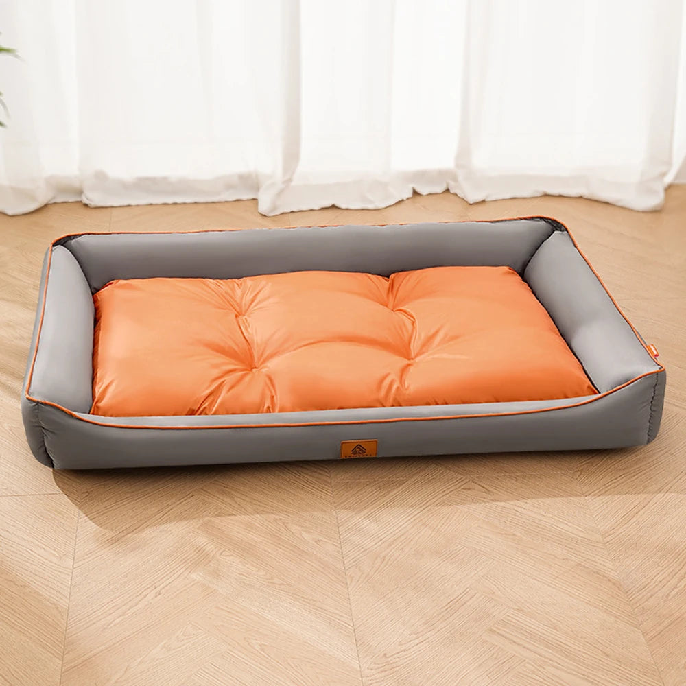 A gray pet sofa bed with an orange quilted cushion placed on a light wooden floor.