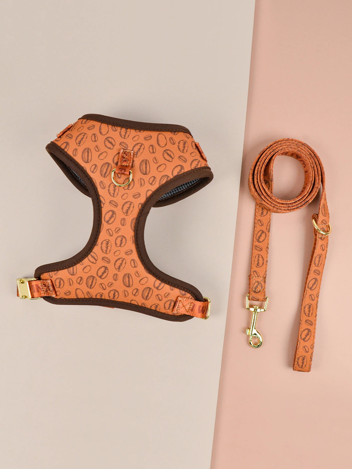 An orange pet harness and matching leather leash displayed on a light pink background.