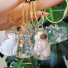 A collection of clear and white glass cat charms hanging from gold-colored chains.
