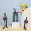 A set of stainless steel pet nail clippers for dogs and cats displayed against a light blue background with yellow flowers.
