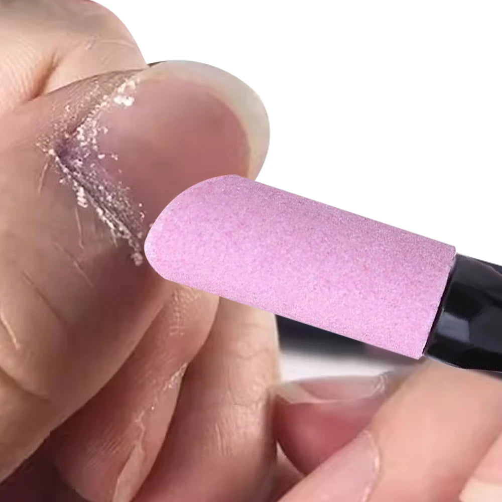 A hand applies a pink nail file cuticle pusher and buffer tool to a fingernail.