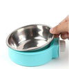 A hand is holding a stainless steel hanging dog bowl with a light blue base.