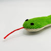 A bright green crinkle cat toy shaped like a frog with black eyes and a red string tail.