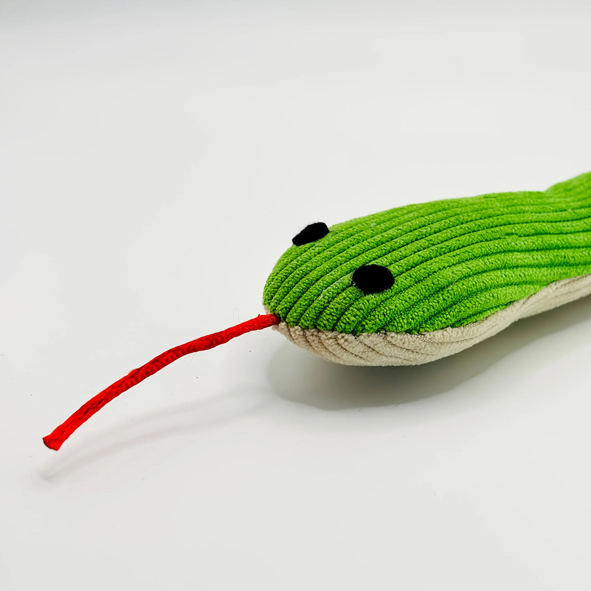 A bright green crinkle cat toy shaped like a frog with black eyes and a red string tail.